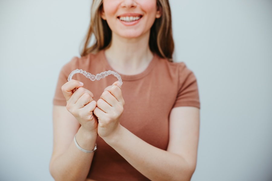 woman holding Invisalign clear aligners in a heart shape
