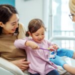 child in mother's lap at dentist for a first dental visit